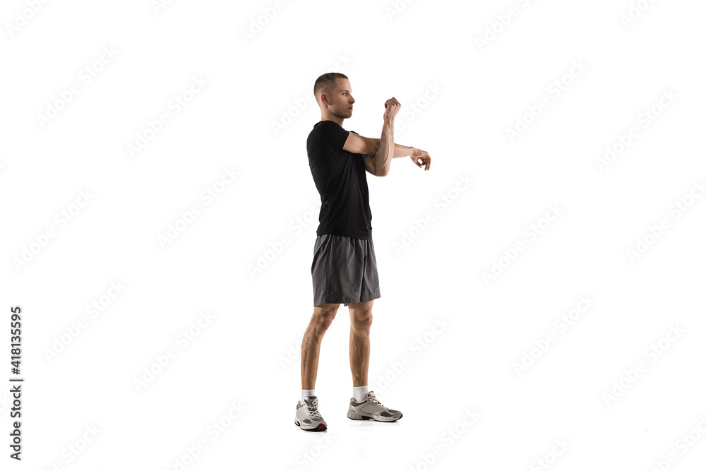 Obraz premium Stretching. Young caucasian male model in action, motion isolated on white background with copyspace. Concept of sport, movement, energy and dynamic, healthy lifestyle. Training, practicing. Authentic