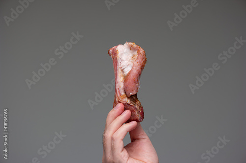 Fototapeta Naklejka Na Ścianę i Meble -  Raw seasoned sliced pork rib held by Caucasian male hand studio shot isolated on gray background