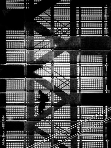 Czarno-białe graficzne pionowe ujęcie mężczyzny na metalowej klatce schodowej