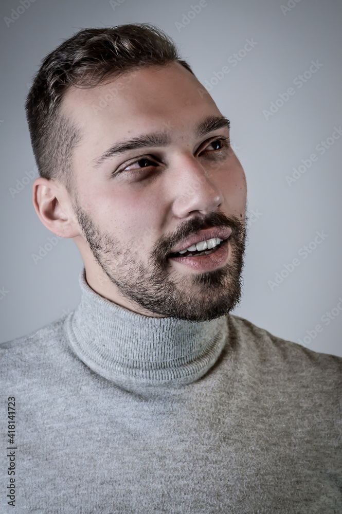 Portrait of a young brown-haired man with a short beard and a gray turtleneck sweater Portrait of a young brown-haired man with a short beard and a gray turtleneck sweater