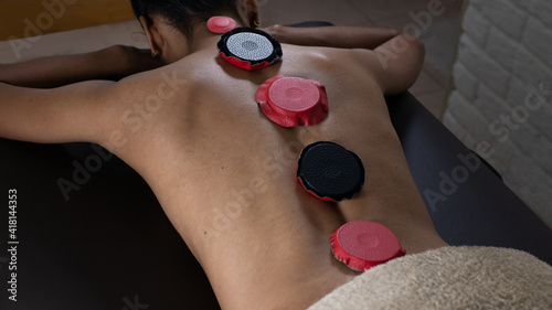 Brunette woman lying on a therapeutic stretcher with biomagnetism therapy magnets placed on her spine to treat her health with holistic therapies and alternative medicine