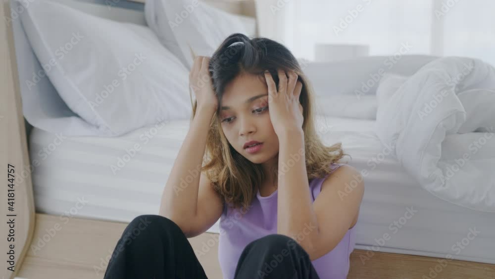 Medium shot – Sad young Asian woman suffering from depressive disorder isolate herself and desperately sitting alone in white bedroom. Woman with mental health suffering from depression. Medium shot – Sad young Asian woman suffering from depressive disorder isolate herself and desperately sitting alone in white bedroom. Woman with mental health suffering from depression.