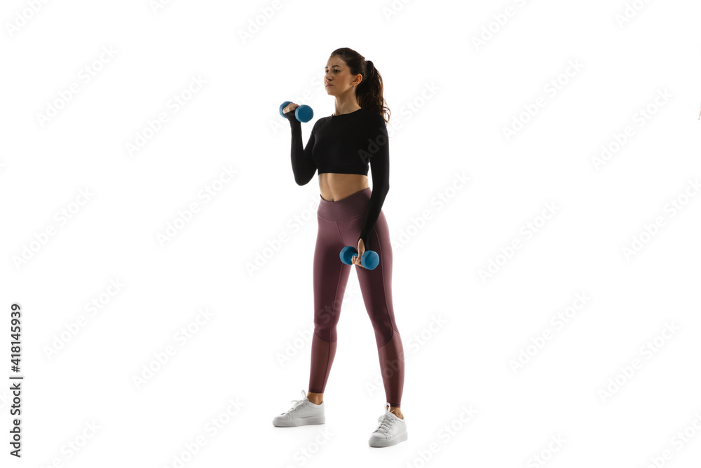 Dumbbells. Young caucasian female model in action, motion isolated on white background with copyspace. Concept of sport, movement, energy and dynamic, healthy lifestyle. Training, practicing.