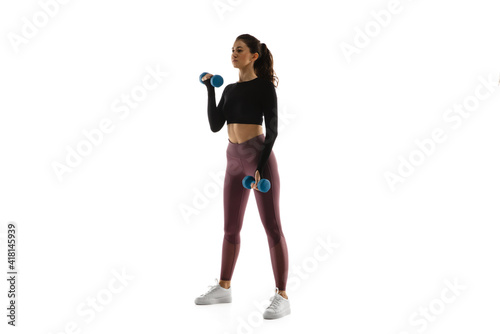 Dumbbells. Young caucasian female model in action, motion isolated on white background with copyspace. Concept of sport, movement, energy and dynamic, healthy lifestyle. Training, practicing.
