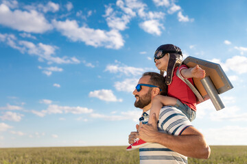 Father and son playing against blue summer sky background