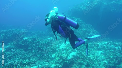 Underwater scene with a single young male Scuba diver exploring and diving into the Easter Islands' Sea Life Reef at Rapa Nui, Chile, with on back a clear turquoise blue deep Pacific Ocean. photo