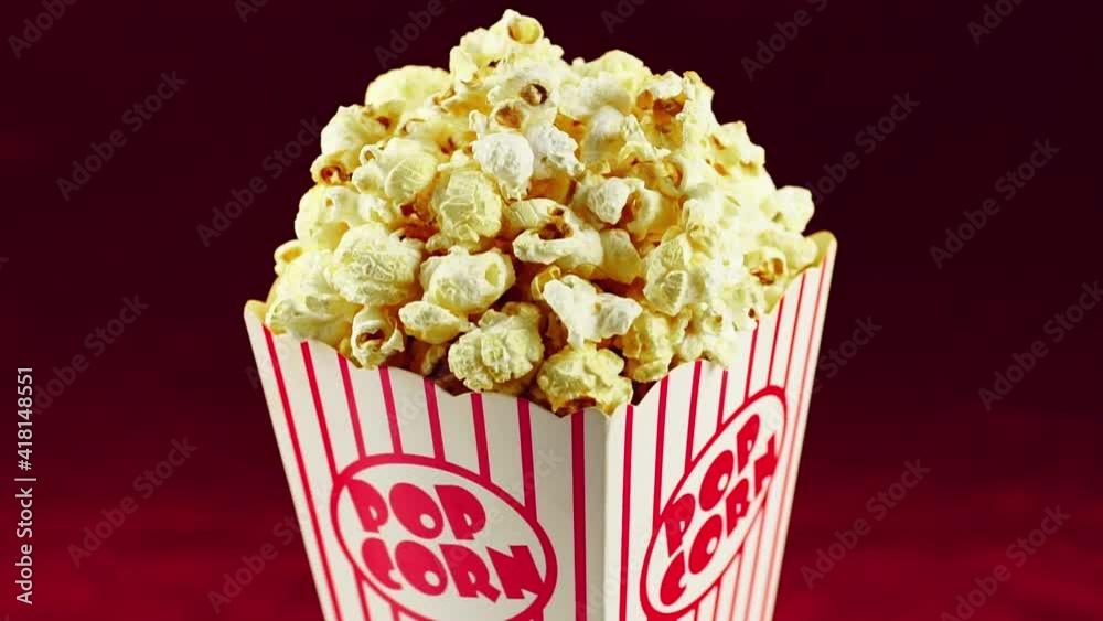 Full popcorn in a classic popcorn box on a red background.Popcorn