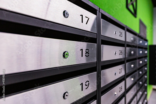 Mailboxes in an apartment building, made of stainless steel, on a green wall