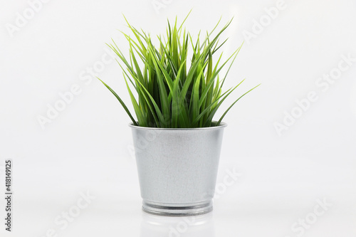 Artificial green grass in galvanize steel pot on white