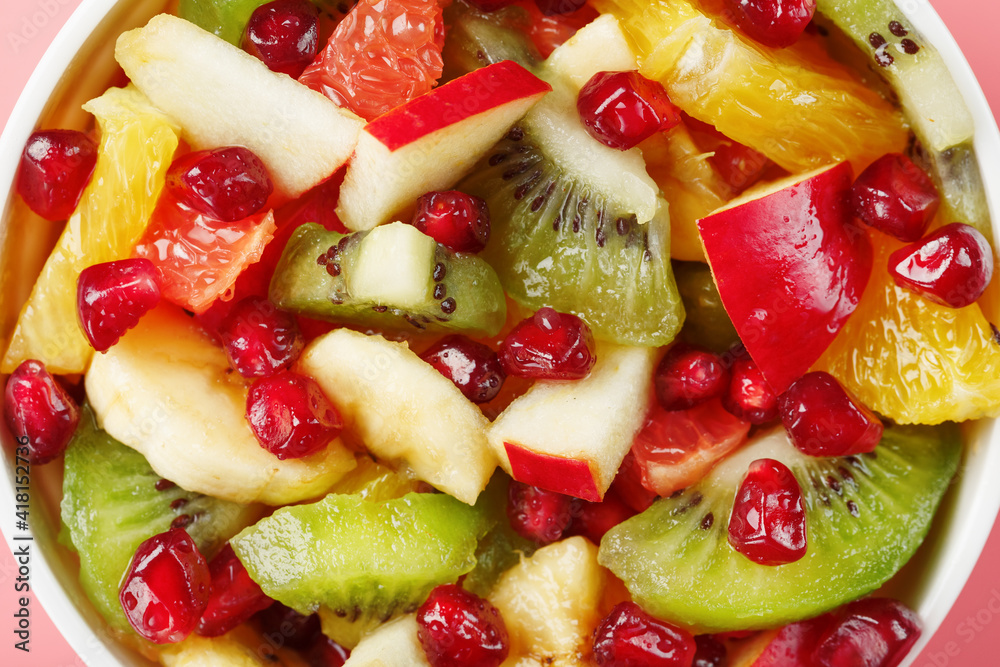 Salad of different juicy ripe fruits in a white cup on a pink background. Salad of different juicy ripe fruits in a white cup on a pink background.