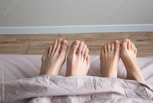 Man and woman legs on bed. Couples feet in bed, close up. Good morning.