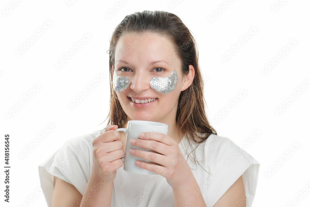 Happy woman with cup and collagen pads under her eyes. Morning routine Happy woman with cup and collagen pads under her eyes. Morning routine