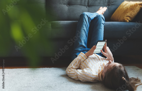 Tween girl with smartphone relaxing at home.