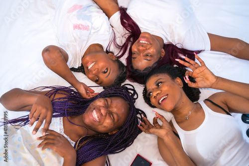 Lifestyle of friends in a hotel bed, friends of black ethnicity. Smiling and looking at each other photo