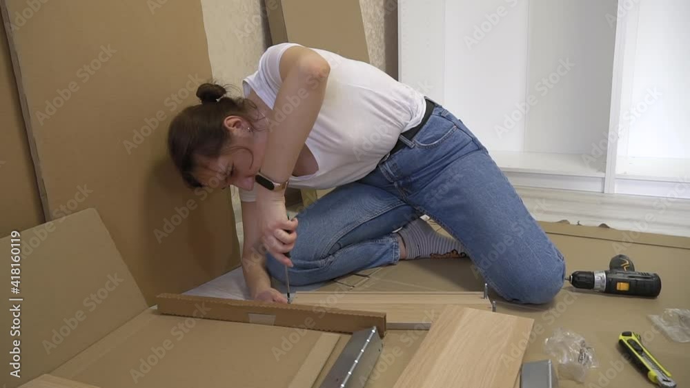 Woman doing it yourself furniture assembly twist the screw by screwdriver. Moving in new house Woman doing it yourself furniture assembly twist the screw by screwdriver. Moving in new house