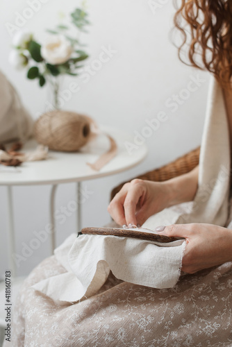 A woman's hands are embroidered on linen cloth. A woman holds an embroidery frame. photo