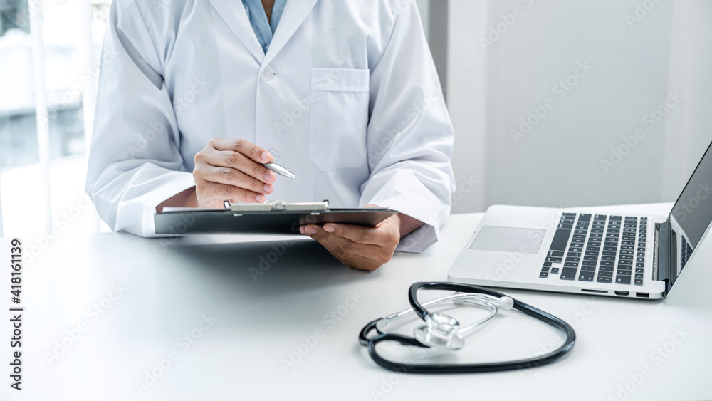 Doctor is sitting and reading medical report in his hospital office Doctor is sitting and reading medical report in his hospital office