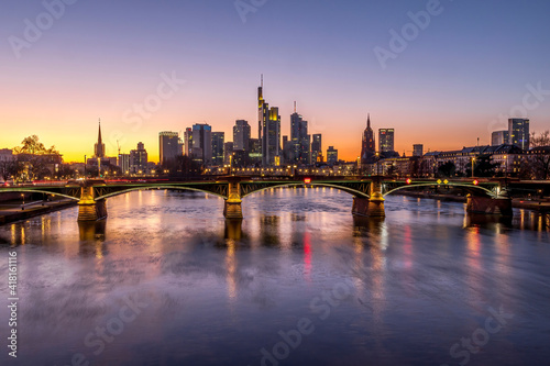 The skyline of Frankfurt at sunset, seen from a bridge at the river Main at a cold day in winter.