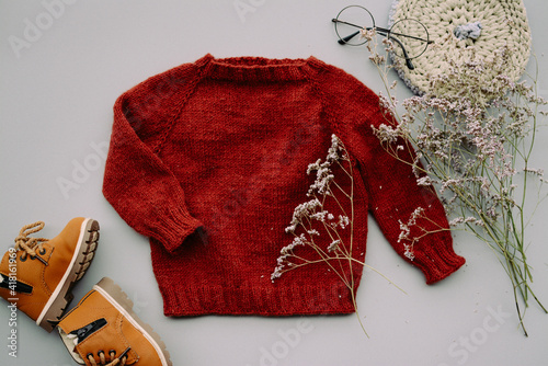 Red woolen handmade baby sweater on gray background