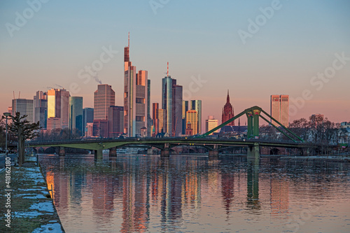 Picture of Frankfurt skyline during sunrise with reflections of skyscraper facades in Main river under cloudless and colorful sky © Aquarius