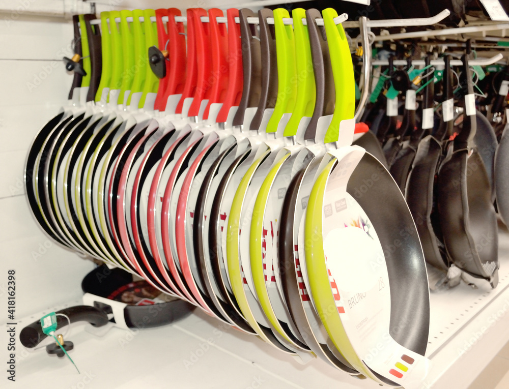 Sale of modern pans with multi-colored handles in the store Sale of modern pans with multi-colored handles in the store