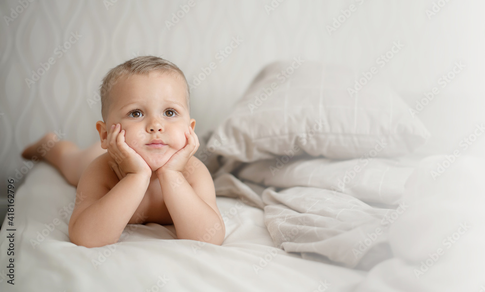 Portrait of one toddler caucasian boy lying on the bed. Copy space, horizontal
