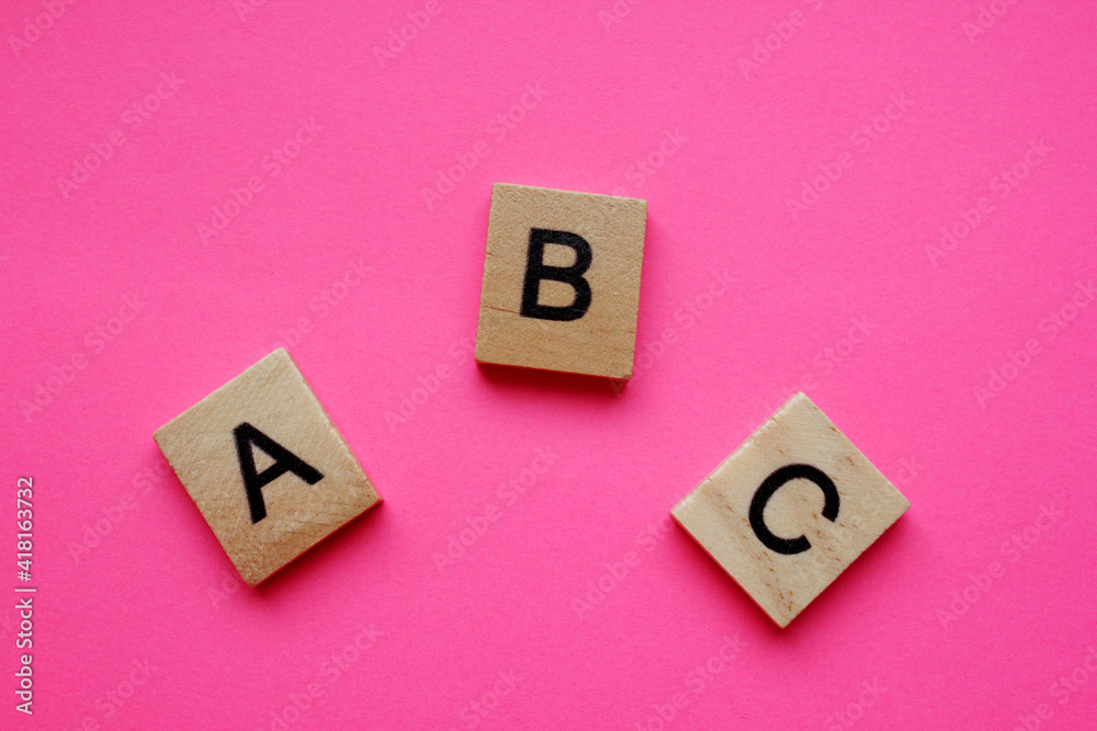 ABC is alphabetical characters on a pink background. Wooden alphabetical blocks, isolated against a pink background. English alphabet. View from above. Words. English language. Grammar. ABC is alphabetical characters on a pink background. Wooden alphabetical blocks, isolated against a pink background. English alphabet. View from above. Words. English language. Grammar.