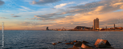  Panoramic view of the coast of Barcelona. Picturesque sunrise over the sea. Pink clouds lit by the first rays of the sun. 