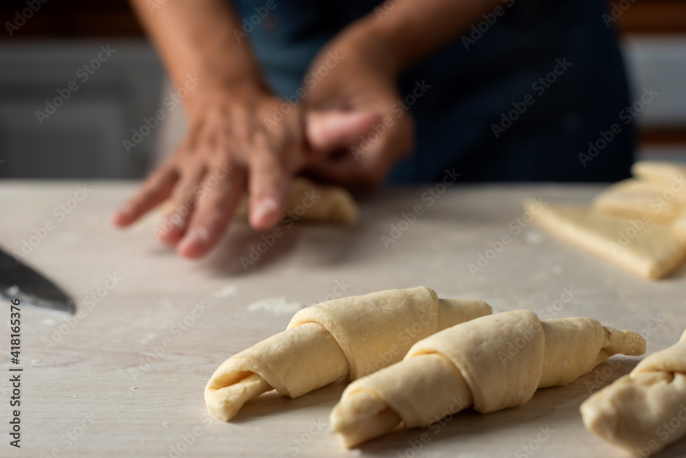 hands assembling and stretching, shaping the croissant dough and croissant into triangles to assemble and bake hands assembling and stretching, shaping the croissant dough and croissant into triangles to assemble and bake