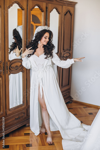 Attractive bride touching her beautiful white dress in the early morning. Trendy wedding style shot. Fashion bride with beautiful hair