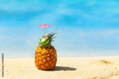 pina colada cocktail in fresh pineapple on the beach by the blue ocean