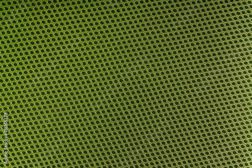 Detailed texture of green fabric with round holes.