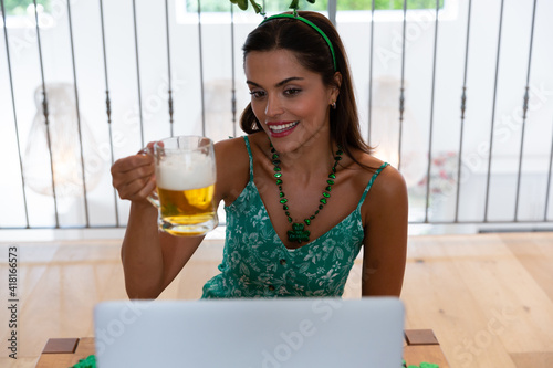 Caucasian woman celebrating st patrick's day making video call wearing deely boppers holding beer photo