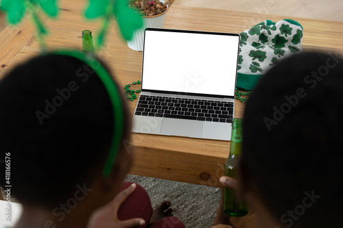 African american couple on st patrick's day video call using laptop with copy space on screen
