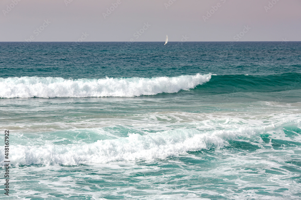 Crystal clear sea water of Mediterranean sea. Sea waves break on the shore after a storm.