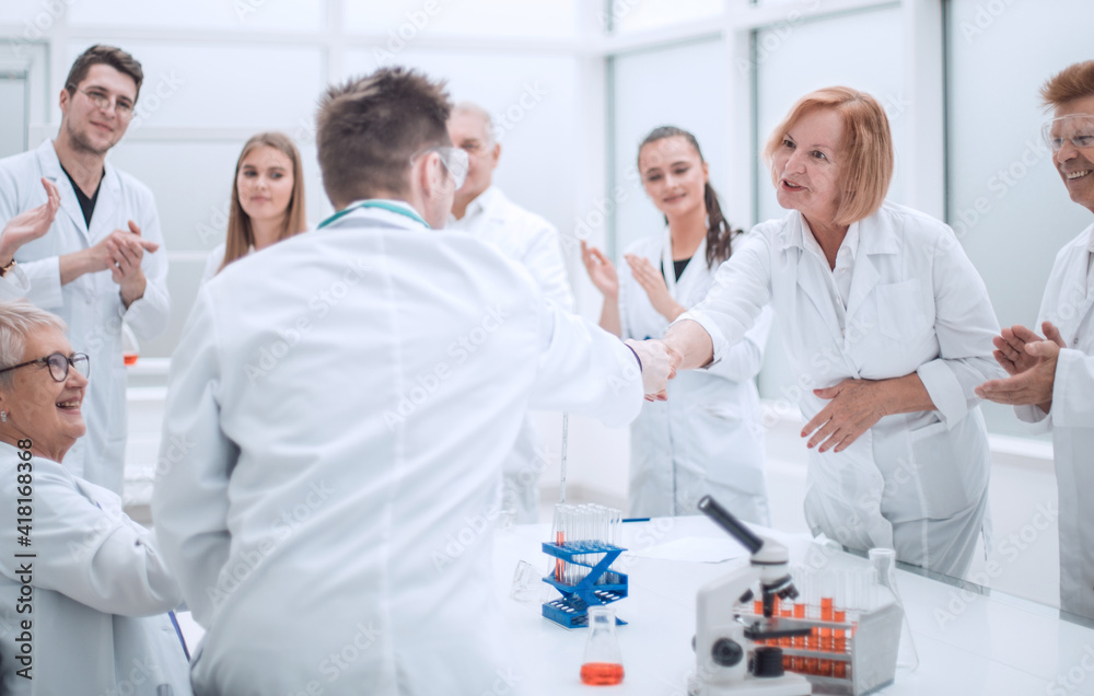 group of scientists congratulating their colleague in the workplace group of scientists congratulating their colleague in the workplace