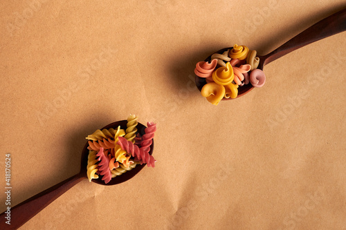 wooden spoons with colorful Italian pasta on top. wooden spoons on paper