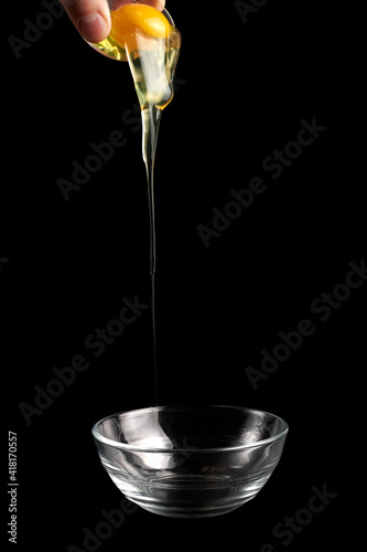 Egg yolk falling frozen on air. Hand pours raw egg yolk into a plate on a black background
