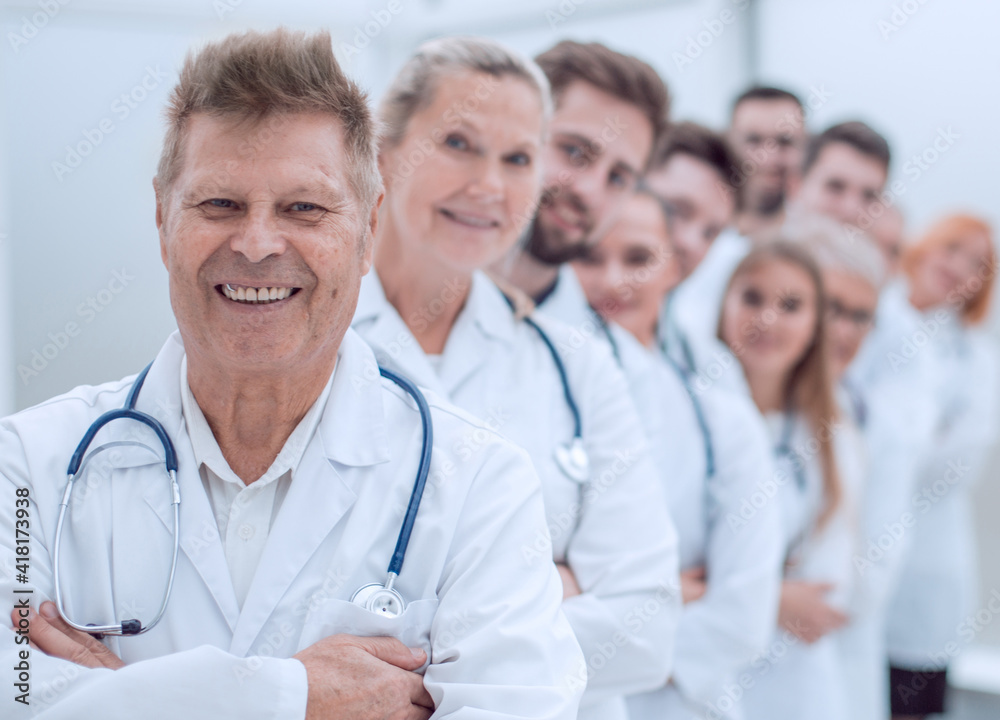 smiling GP standing in front of a group of doctors. smiling GP standing in front of a group of doctors.