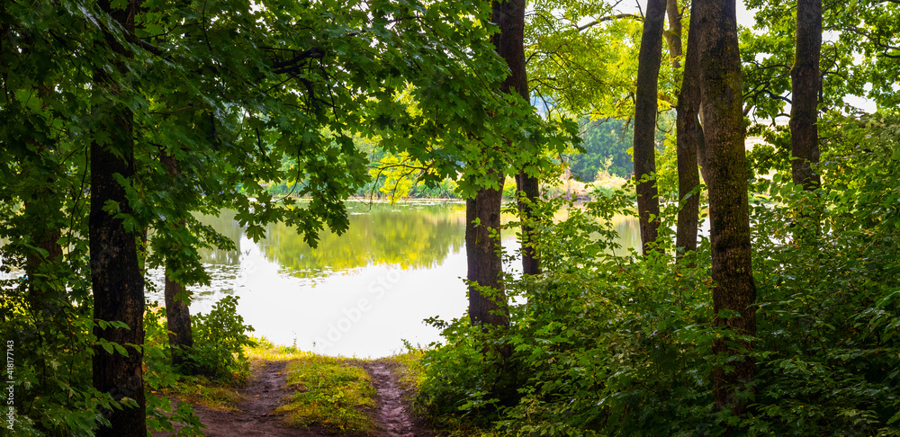 Summer landscape with trees by the river, road from forest to river Summer landscape with trees by the river, road from forest to river
