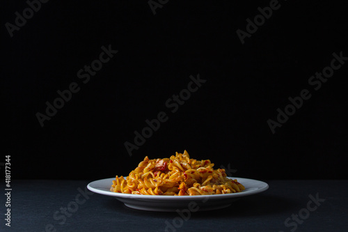 Italian pasta on a dark background. Italian pasta in tomato sauce on a black background. Home traditional cuisine.