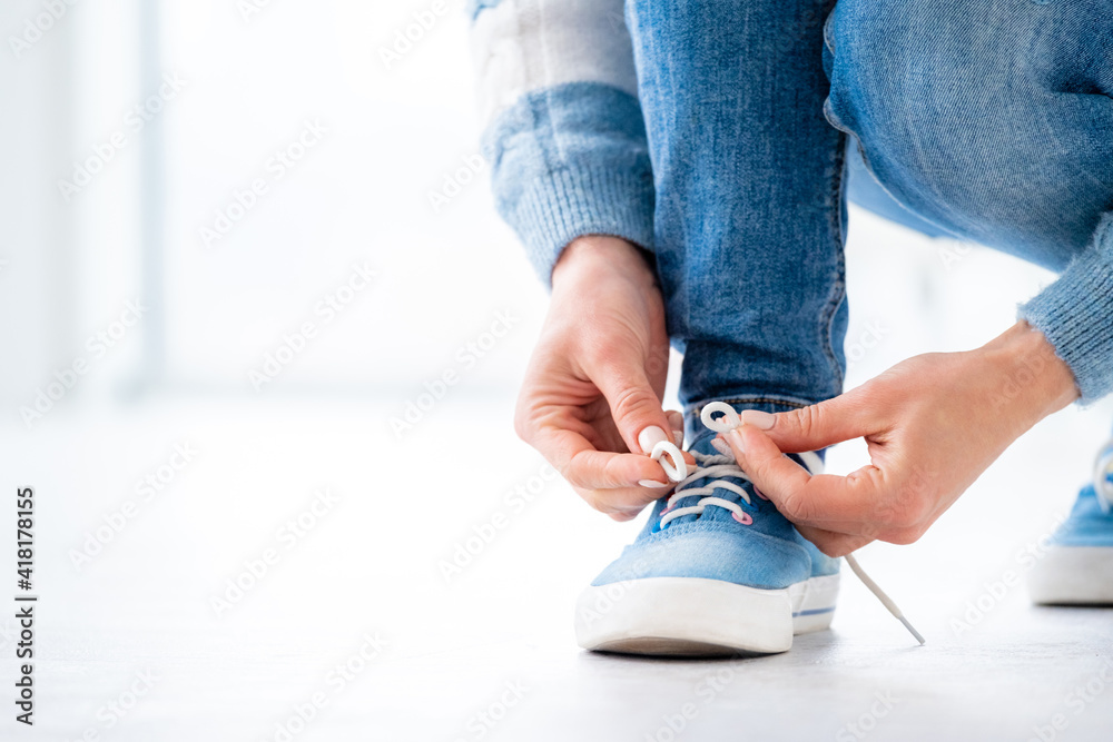 Person tying laces on gumshoes at home