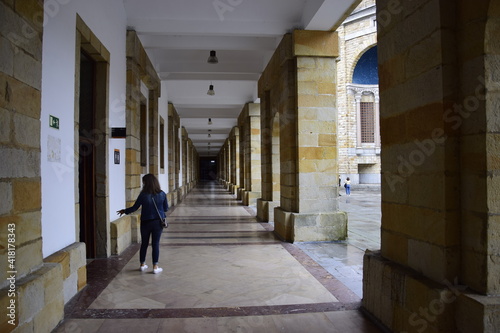 Una mujer sale de un aula hacia uno de los corredores junto al gran patio central de la Antigua Universidad Laboral de Gijón, España