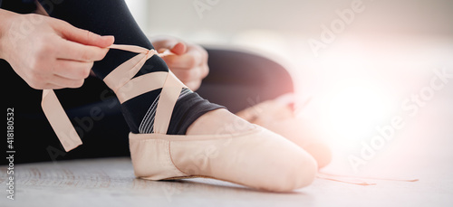 Closeup view on ballerina legs wearing beige pointe shoes in sunlight dance studio