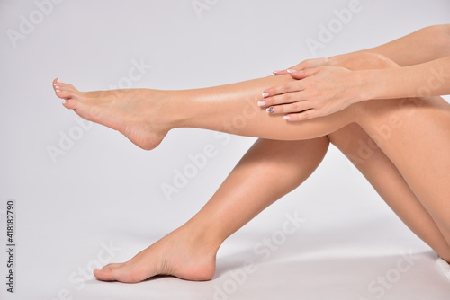 Woman touching her smooth legs after depilation, stock photo