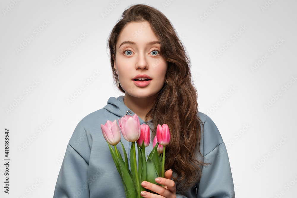 Young woman with tulips. Blue eyes, long hair and surprise on her face. Young woman with tulips. Blue eyes, long hair and surprise on her face.