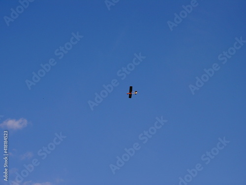 Very small and light propeller plane flying at high altitude, in the background of blue sky, view from bottom from the side