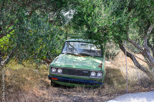 Abandoned car is parked in an olive grove