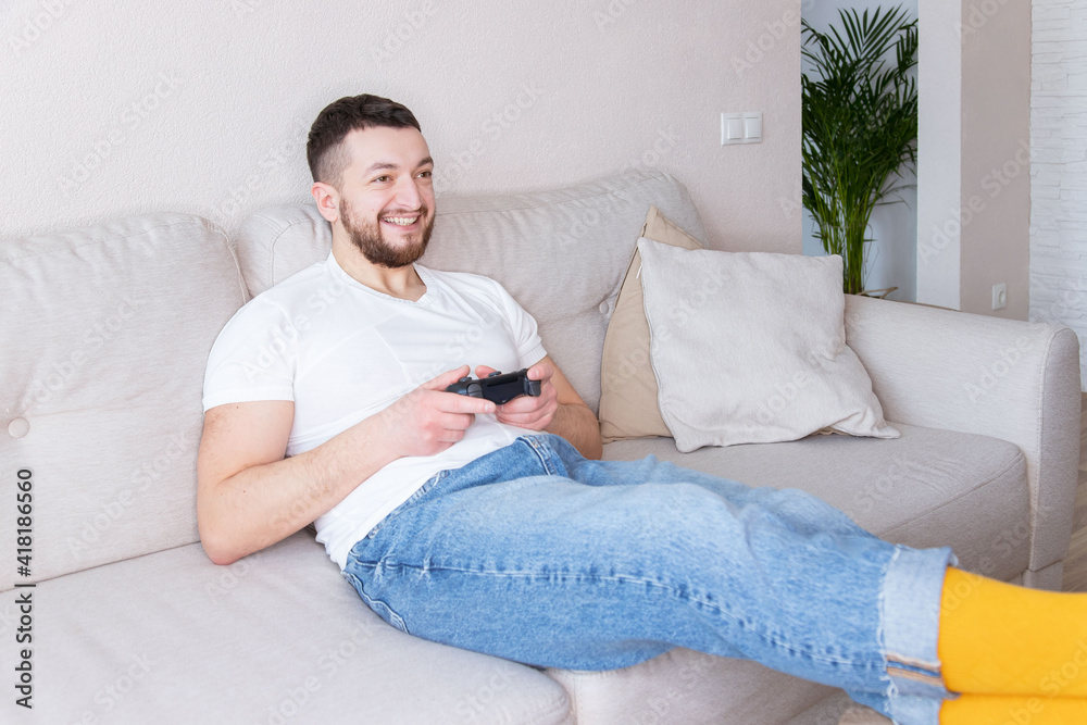 Young man playing video games at home. Happy guy sitting on the couch with joystick in hands. Young man playing video games at home. Happy guy sitting on the couch with joystick in hands.