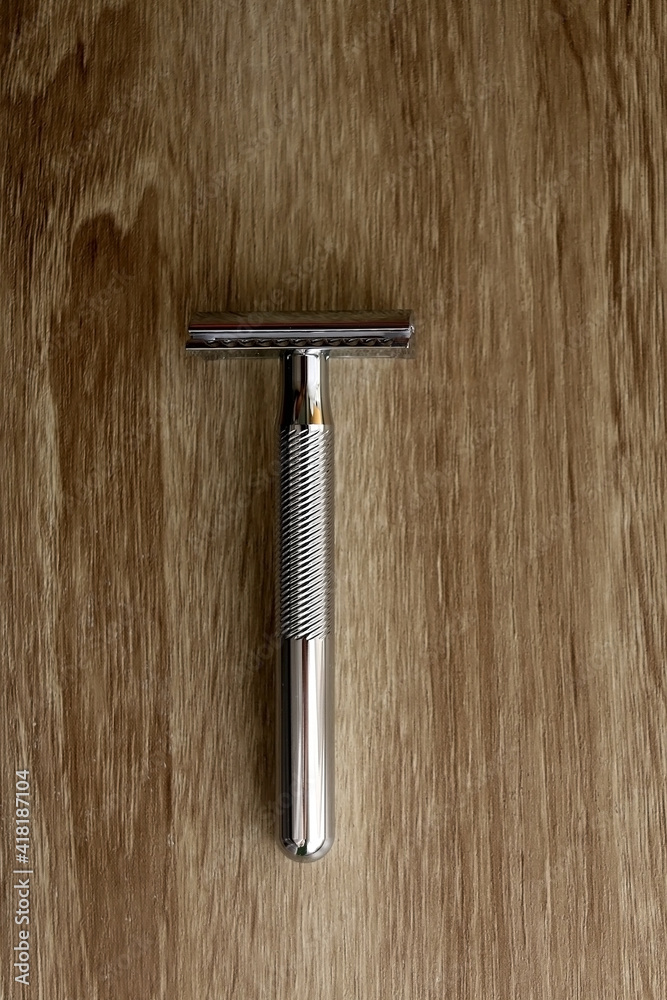 Reusable metal safety razor on wooden background. Top view. Reusable metal safety razor on wooden background. Top view.